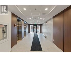 A hallway with a black carpet in the middle and elevators on the left.