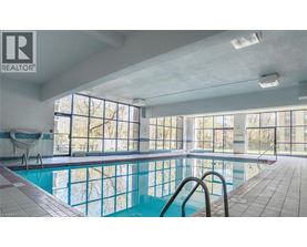 A large indoor swimming pool with a slide and a sunny day outside.