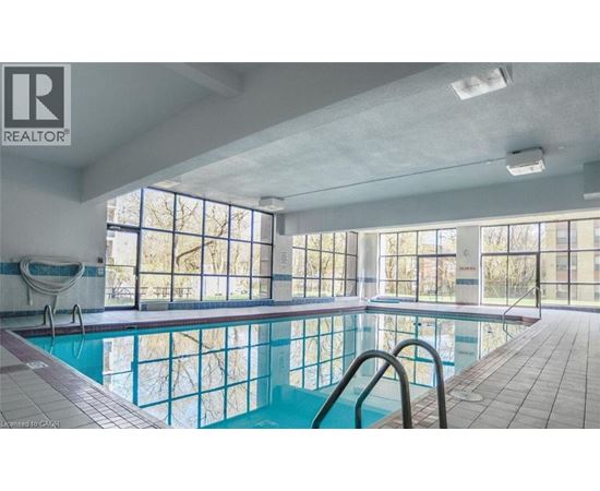 A large indoor swimming pool with a slide and a sunny day outside.
