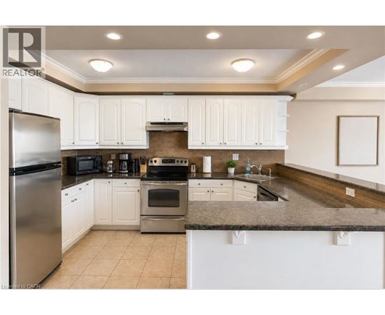 A kitchen with white cabinets and a stainless steel refrigerator.