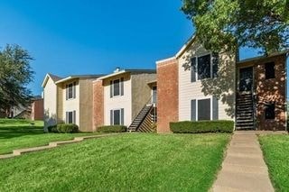 A row of houses with green lawns in front.