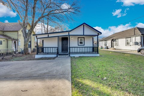 A small house with a black front porch and a blue trim.