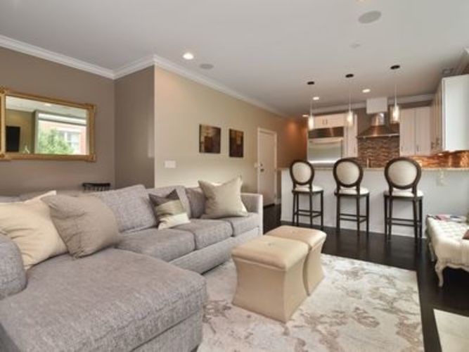 A grey couch with a white ottoman in front of it.