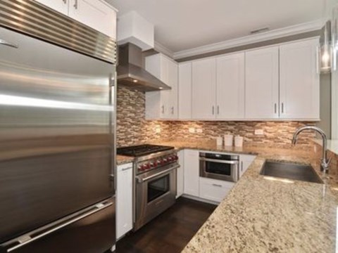 A modern kitchen with a granite countertop and stainless steel appliances.