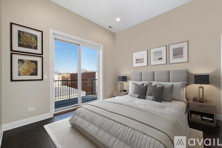 A bedroom with a large bed and a view of a fence and houses outside.