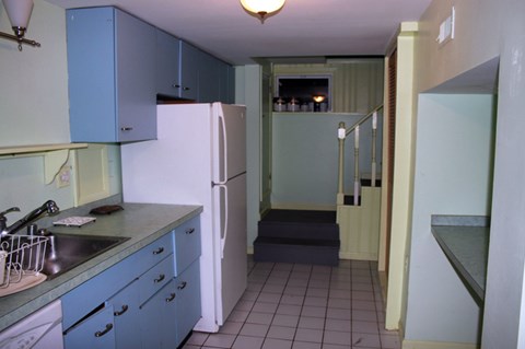 A kitchen with blue cabinets and a white refrigerator.