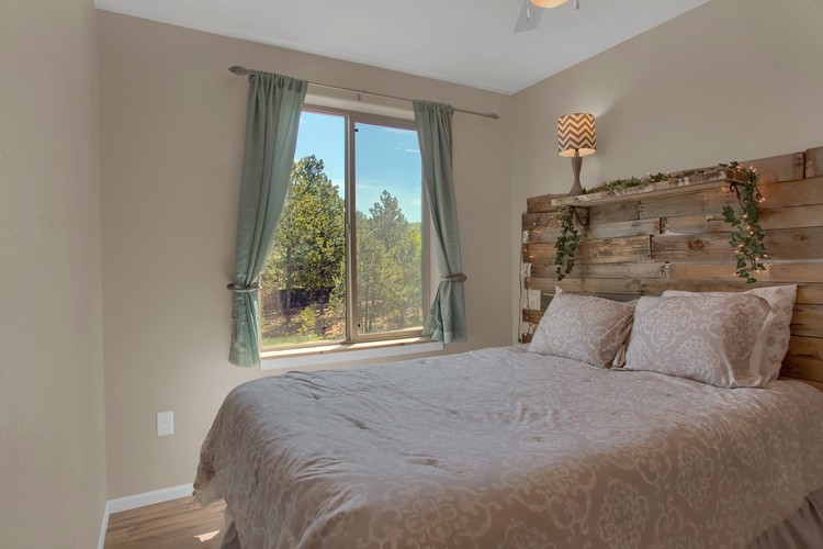 A bedroom with a large bed and a window with green curtains.