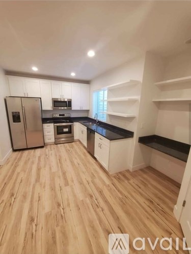 A kitchen with wooden floors and white cabinets.