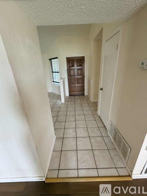 A hallway with a tiled floor and a door at the end.