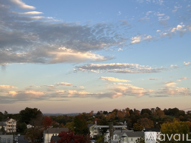 A view of a town from a high vantage point with a mix of clouds and blue sky.