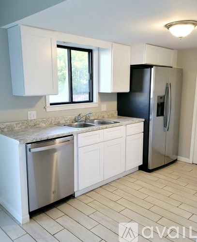 A kitchen with white cabinets and a black refrigerator.