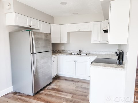A kitchen with a refrigerator, sink, and cabinets.