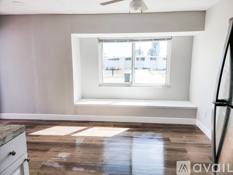 A room with a large window and a fan on the ceiling.