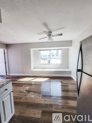 A kitchen with a refrigerator, a ceiling fan, and a window.