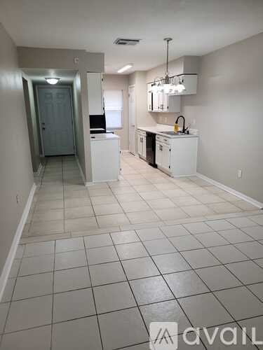 A kitchen with white cabinets and a white tile floor.