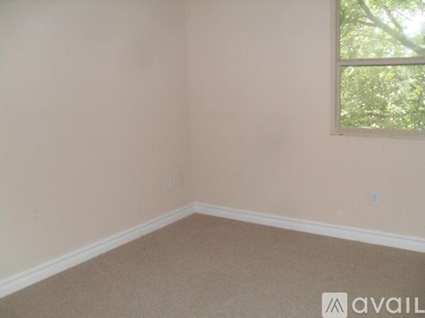 A room with a carpeted floor and a window.