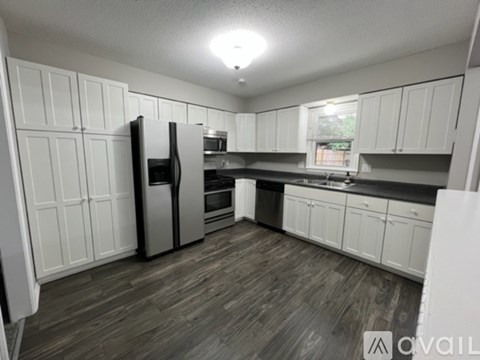 A kitchen with white cabinets and a wooden floor.