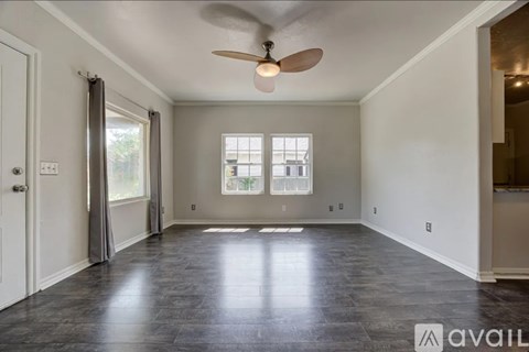 A spacious room with a ceiling fan and large windows.
