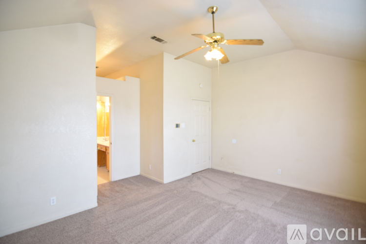 A spacious room with a ceiling fan and carpeted floor.