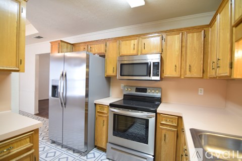 A kitchen with wooden cabinets and a stainless steel refrigerator.