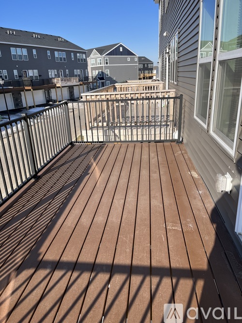 A wooden deck with a metal railing and a building in the background.