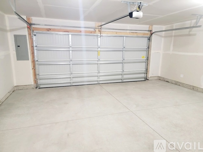 A spacious garage with a closed white roller shutter door.