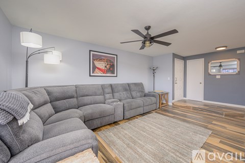 A living room with a grey sofa and a ceiling fan.