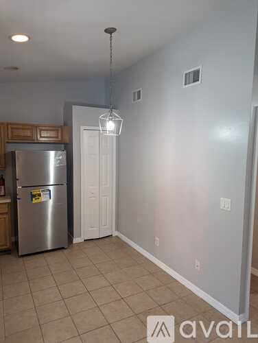 A kitchen with a refrigerator and a door leading to another room.