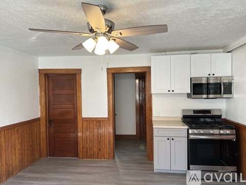 A kitchen with a stove top oven and a ceiling fan.