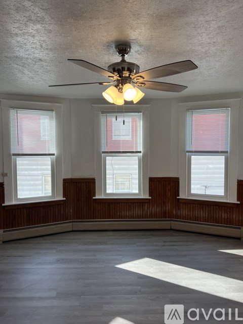 A room with a ceiling fan and windows.