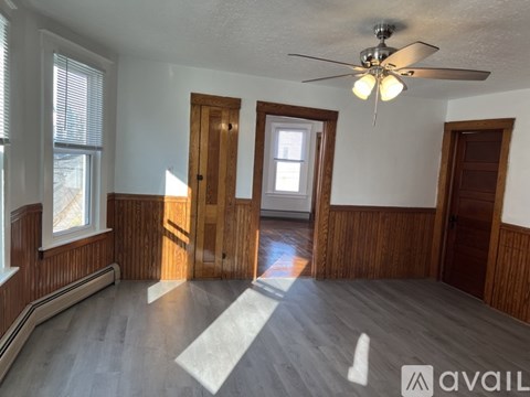 A room with wooden walls and a ceiling fan with lights.