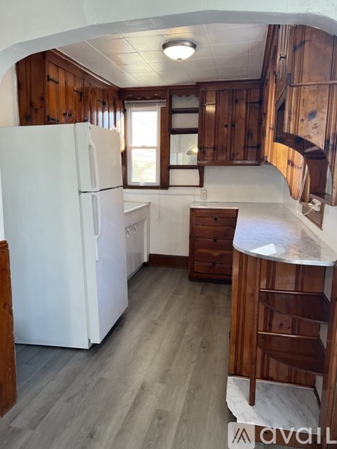 A kitchen with a white refrigerator and wooden cabinets.