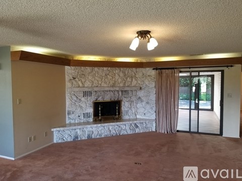 A living room with a fireplace and carpeted floor.