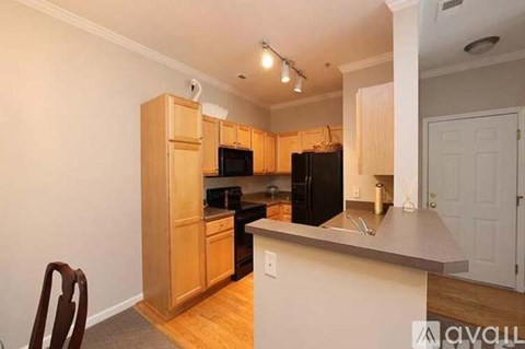 A kitchen with wooden cabinets and a black refrigerator.