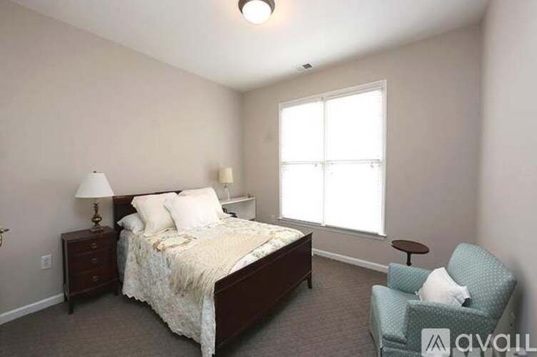 A bedroom with a bed, chair, and two lamps.
