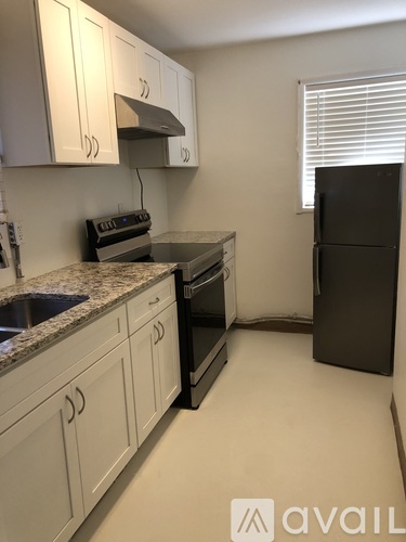 A kitchen with white cabinets and a black refrigerator.