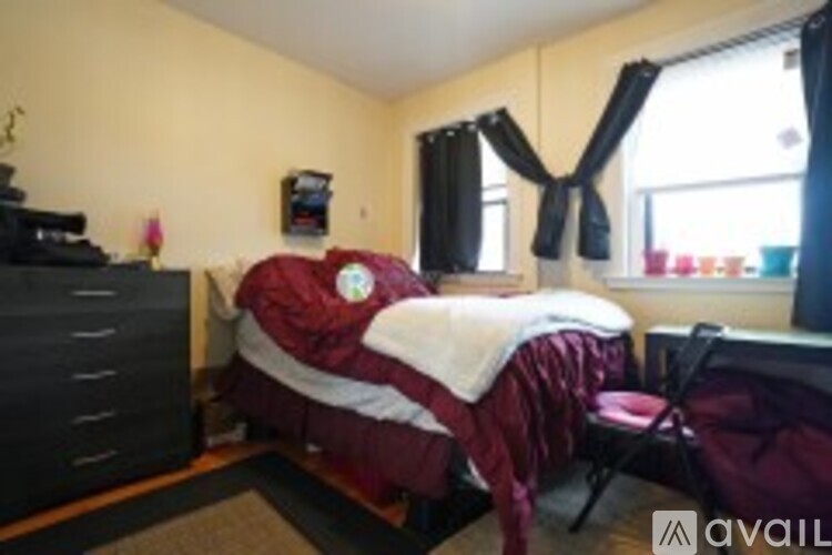 A bedroom with a bed, chair, and window.