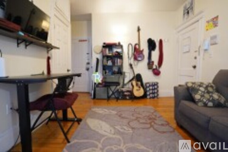 A living room with a couch, a chair, a guitar, a drum set, and a keyboard.