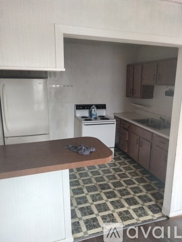 A kitchen with a white fridge, white dishwasher, and a black and white checkered floor.