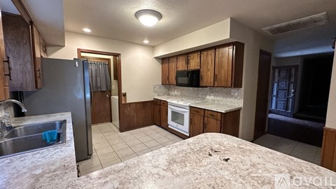 A kitchen with a refrigerator, sink, and microwave.