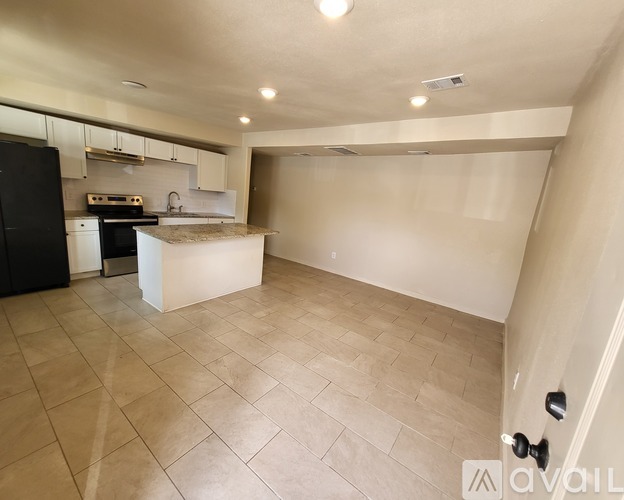 A kitchen with a black refrigerator and a countertop with a sink.
