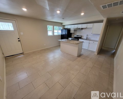 A kitchen with a black fridge and white cabinets.