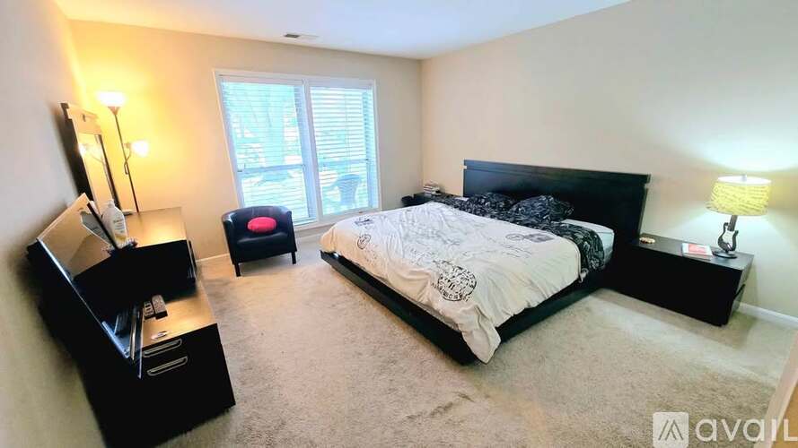 A bedroom with a large bed, a desk with a chair, and two lamps.