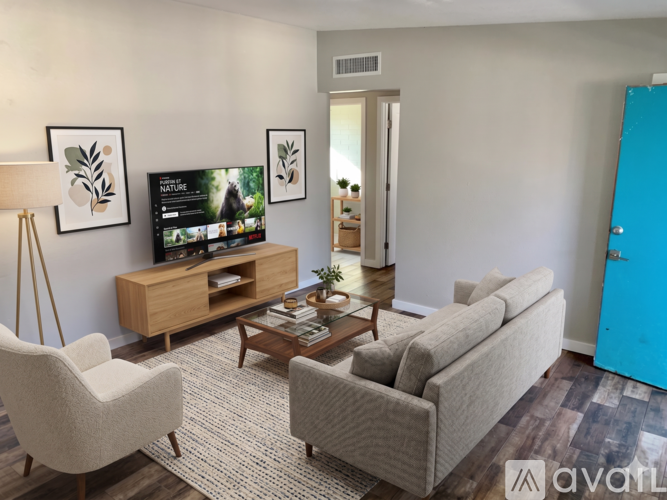 A living room with a television, two chairs, a sofa, and a coffee table.