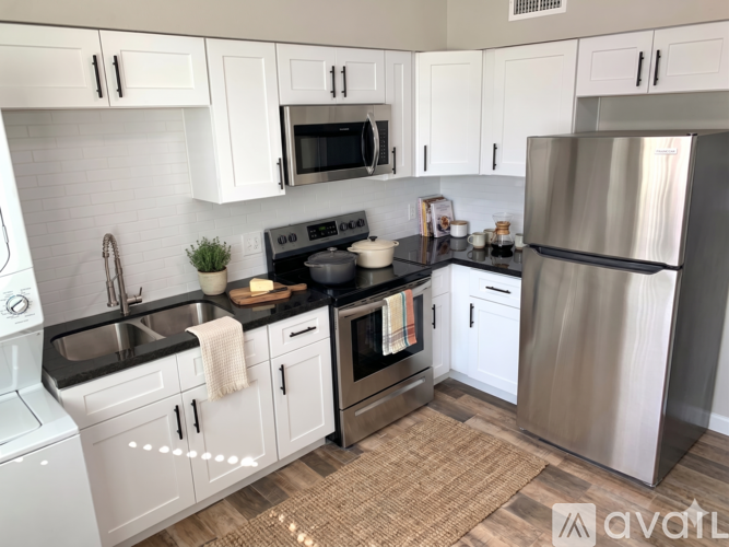A kitchen with white cabinets and a black countertop.