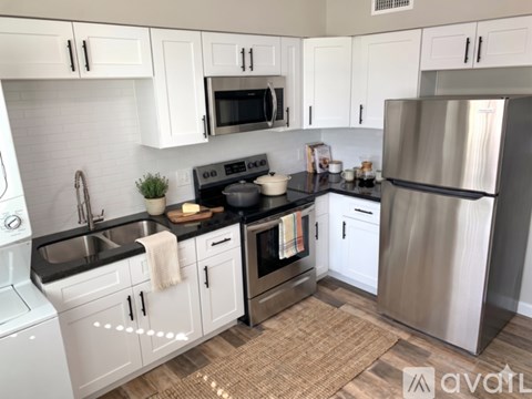 A kitchen with white cabinets and a black countertop.