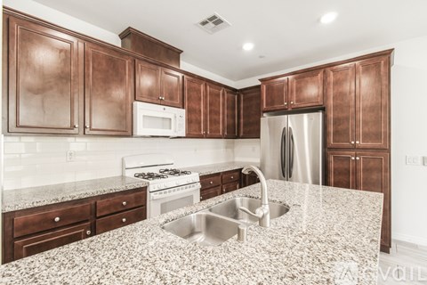 A kitchen with brown cabinets and a granite countertop.