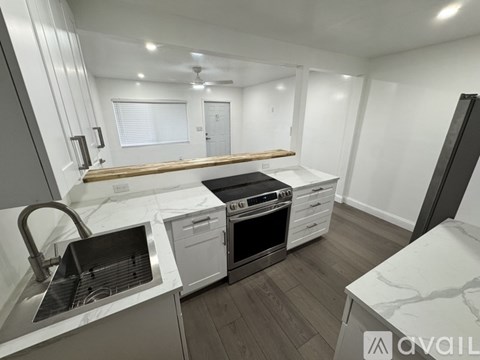 A modern kitchen with a stainless steel sink and a white countertop.