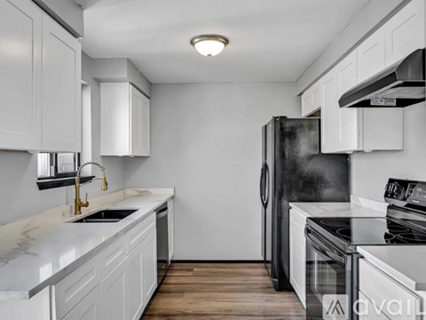 A kitchen with white cabinets and a black refrigerator.