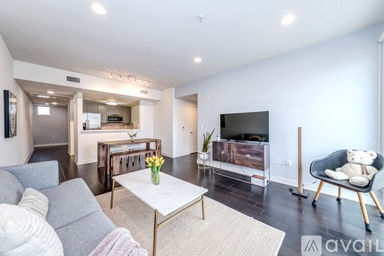 A living room with a grey sofa, a white coffee table, and a TV on the wall.